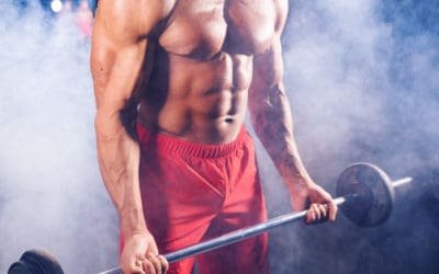 Powerful bodybuilder doing the exercises with barbell. Photo of strong male with naked torso on dark background. Strength and motivation.